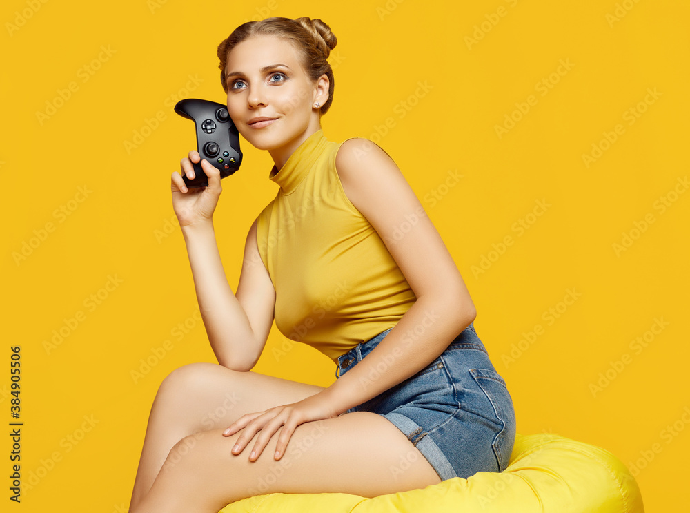 Obraz premium Gorgeous happy blonde gamer girl playing video games using joystick