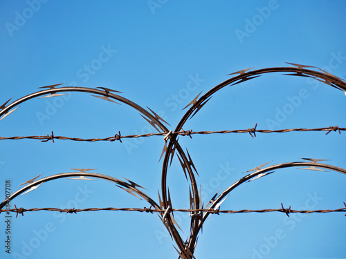 Close-Up Of Razor Wire and Barbed Wire against blue sky