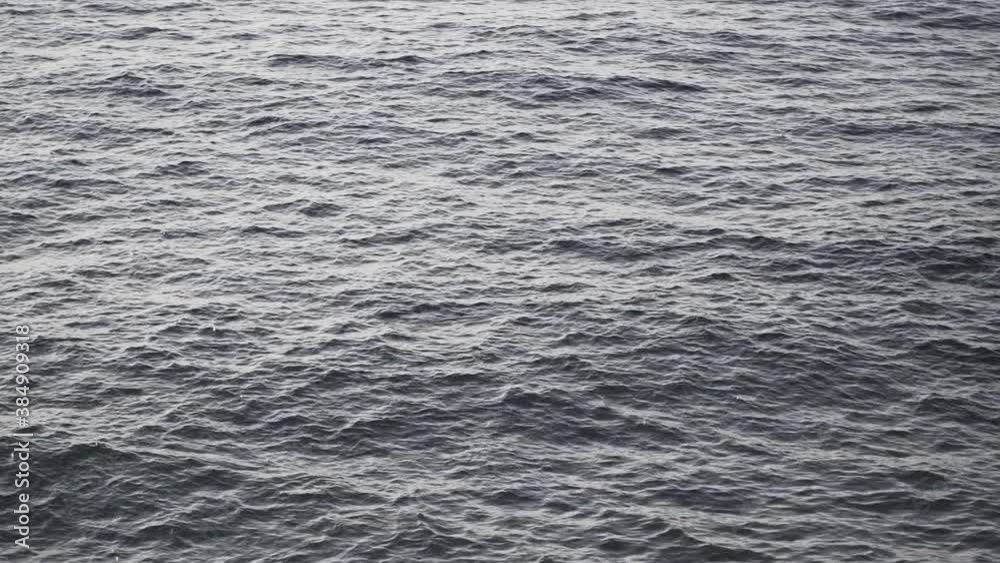 Calm waves rolling to the rocky mountain shoreline of Mallorca - tilt down