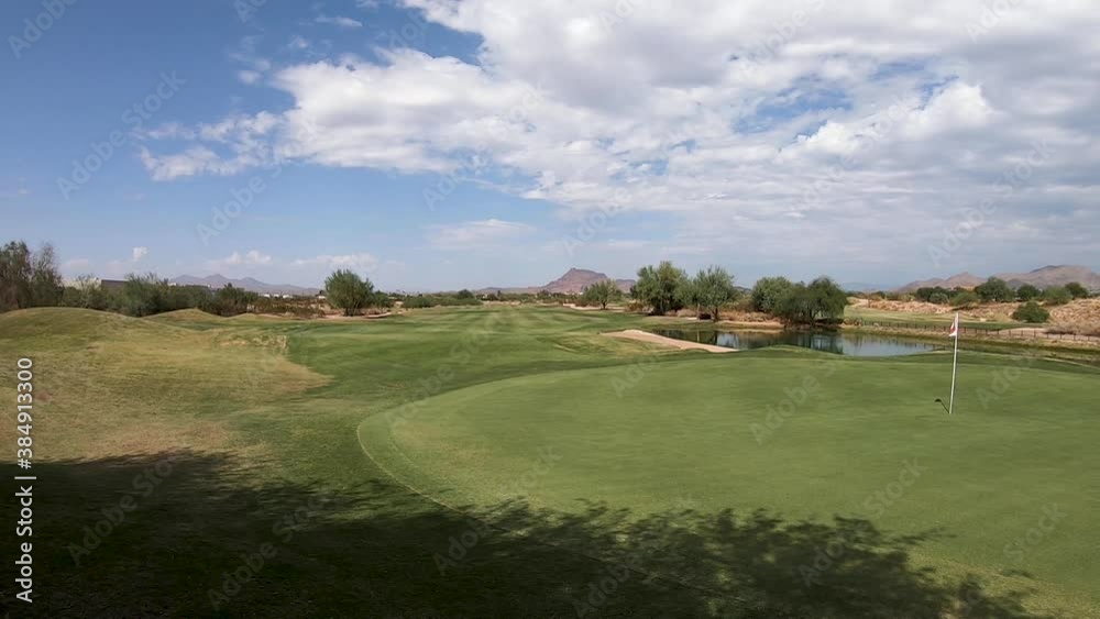 Pan across a distant green and pin, fairway, and water hazard at a golf course in Scottsdale, Arizona. Pan across a distant green and pin, fairway, and water hazard at a golf course in Scottsdale, Arizona.