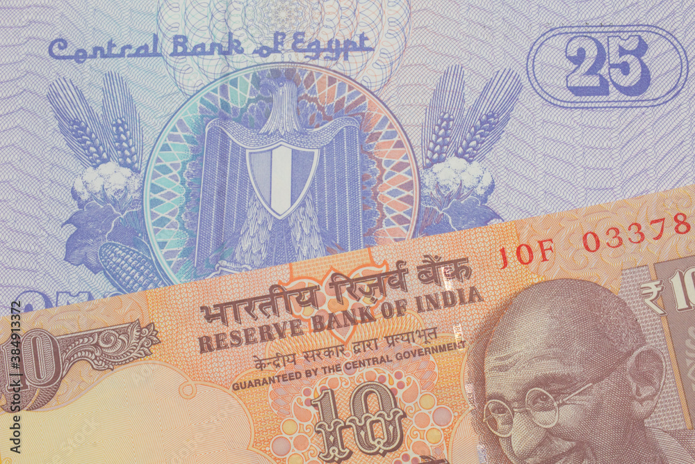 Fototapeta premium A macro image of a orange ten rupee bill from India paired up with a blue twenty five piastre bank note from Egypt. Shot close up in macro.