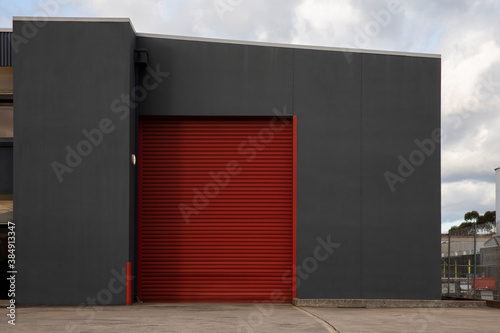 Large industrial red roller door system facade on modern dispatch outlet.