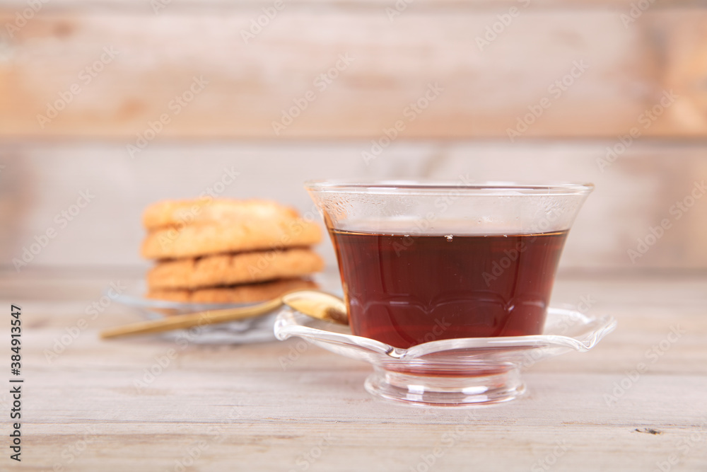 A bowl of hot black tea and a plate of refreshments on a wooden background A bowl of hot black tea and a plate of refreshments on a wooden background