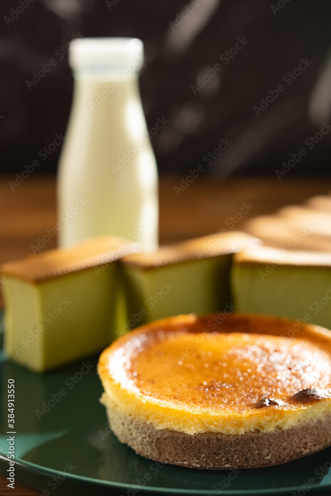 side view cheese cake with matcha cakes and bottle of milk at background in a sunny morning vertical composition side view cheese cake with matcha cakes and bottle of milk at background in a sunny morning vertical composition