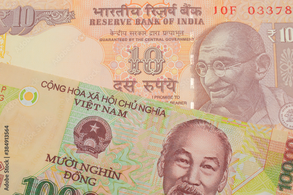 Fototapeta premium A macro image of a orange ten rupee bill from India paired up with a colorful, plastic ten thousand dong note from Vietnam. Shot close up in macro.