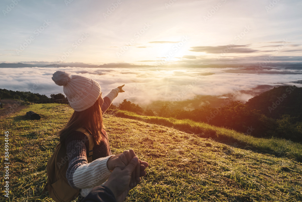 Young couple travelers looking at the sunrise and the sea of mist on the mountain in the morning, Travel lifestyle concept - obrazy, fototapety, plakaty 