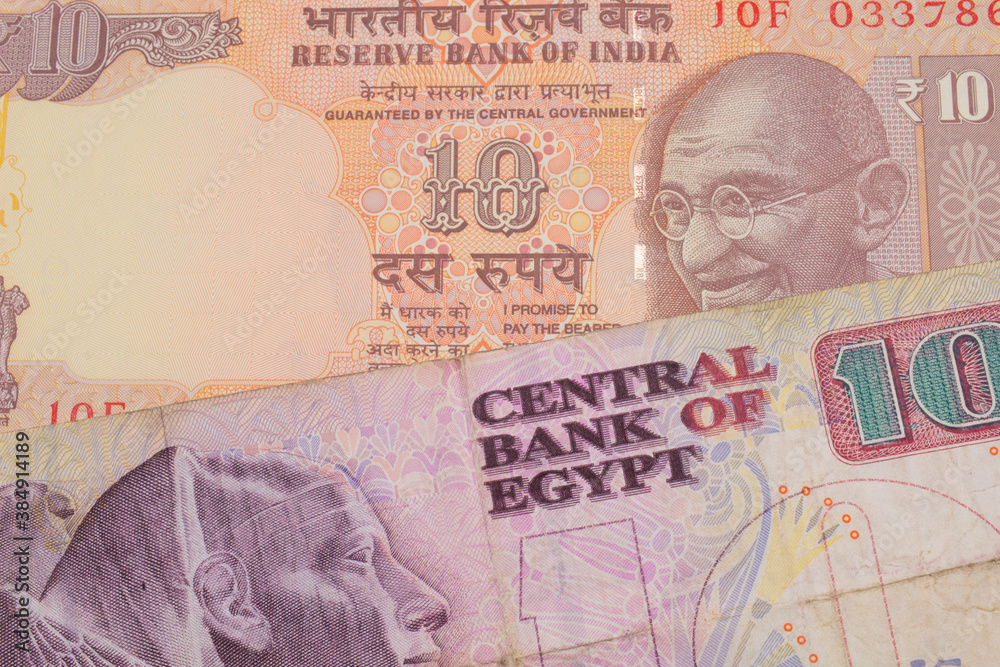 A macro image of a orange ten rupee bill from India paired up with a pink and purple ten pound bank note from Egypt.  Shot close up in macro.