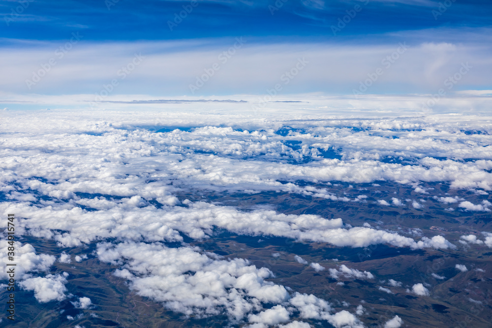 Aerial view above the clouds and mountain peaks on a sunny day.mountain view from airplane. Aerial view above the clouds and mountain peaks on a sunny day.mountain view from airplane.