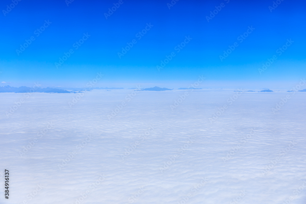Aerial view above the clouds and mountain peaks on a sunny day.mountain view from airplane. Aerial view above the clouds and mountain peaks on a sunny day.mountain view from airplane.