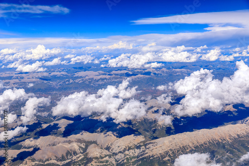 Wallpaper Mural Aerial view above the clouds and mountain peaks on a sunny day.mountain view from airplane. Torontodigital.ca