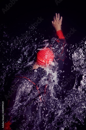 triathlon athlete swimming in dark night wearing wetsuit © .shock