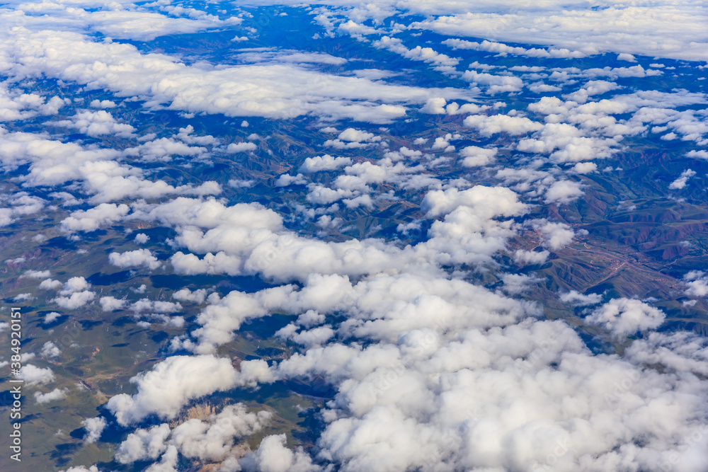 Aerial view above the clouds and mountain peaks on a sunny day.