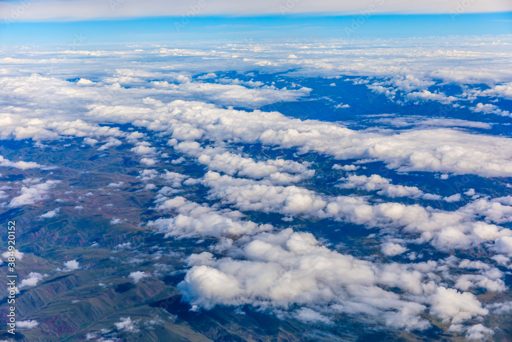 Aerial view above the clouds and mountain peaks on a sunny day.mountain view from airplane. Aerial view above the clouds and mountain peaks on a sunny day.mountain view from airplane.