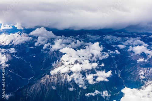 Aerial view above the clouds and misty mountain peaks covered with snow on a sunny day.China Tibet.