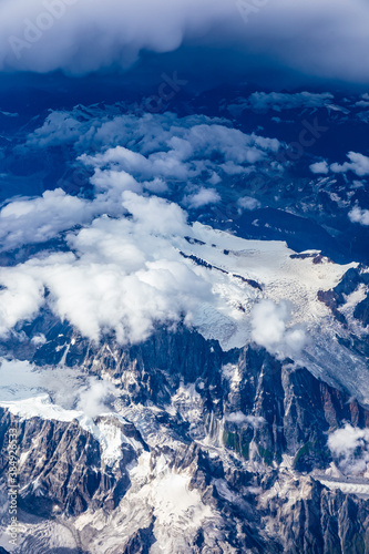 Aerial view above the clouds and misty mountain peaks covered with snow on a sunny day.China Tibet.