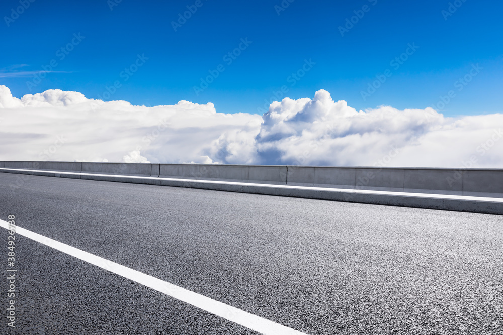 Fototapeta premium Empty asphalt road and blue sky with white clouds scenery.