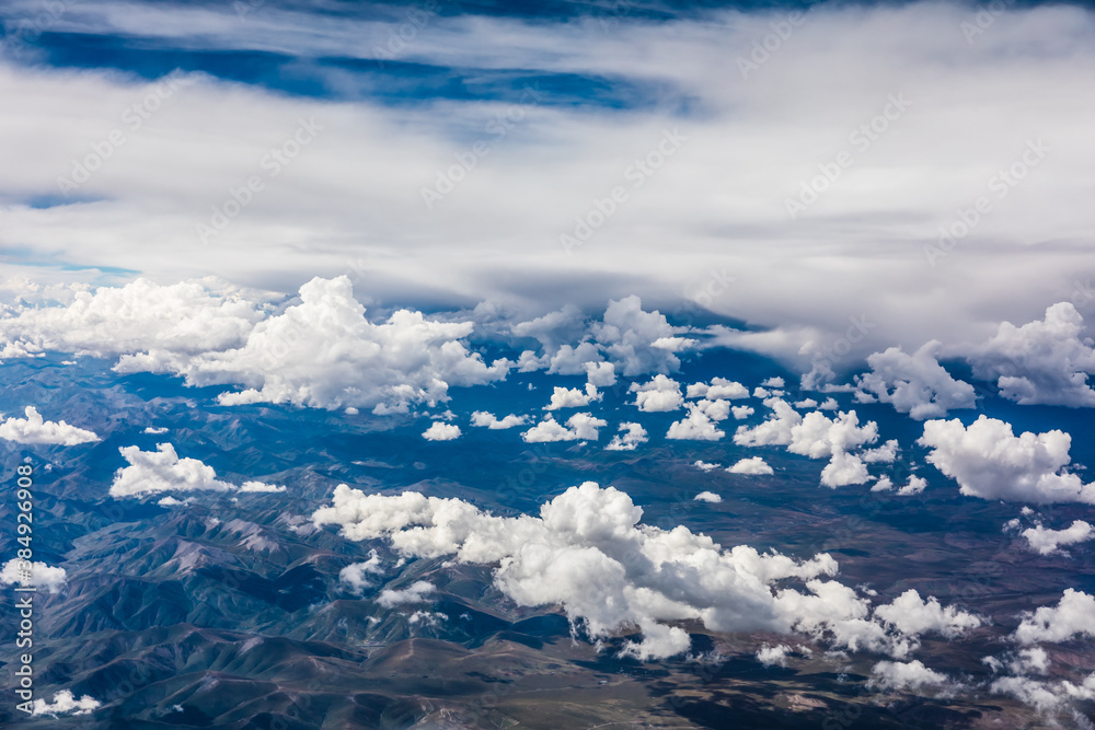 Aerial view above the clouds and mountain peaks on a sunny day.mountain view from airplane. Aerial view above the clouds and mountain peaks on a sunny day.mountain view from airplane.