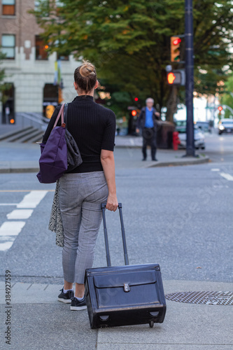 office worker crossing road with her black briefcase in downtown Vancouver. Street photo, selective focus, copyspace for text, travel photo.
