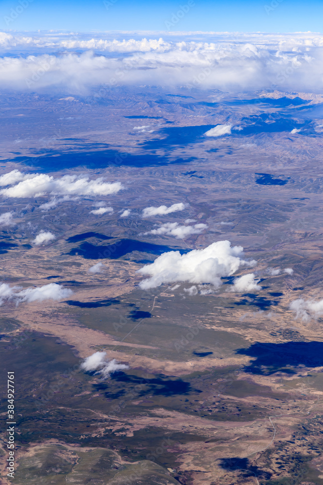 Fototapeta premium Aerial view above the clouds and mountain peaks on a sunny day.mountain view from airplane.