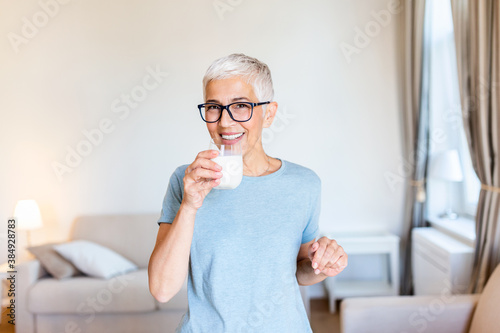 Senior woman's hands holding a glass of milk. Happy senior woman having fun while drinking milk at home. Senior Woman drinking a glass of milk to maintain her wellbeing.