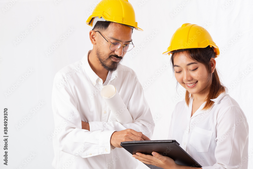 Pretty Architect and Young Engineer in construction helmets talking and discussing, Using Digital Tablet Computer, Working together with isolated on white background. Pretty Architect and Young Engineer in construction helmets talking and discussing, Using Digital Tablet Computer, Working together with isolated on white background.
