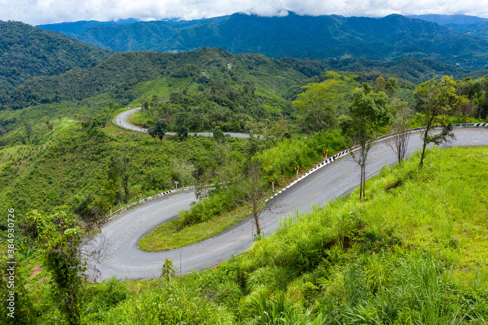 Winding road, top view of the corner Look at the beautiful aerial view of asphalt roads, highways through mountains and forests in rainy season. For traveling and driving in nature. Nan thailand