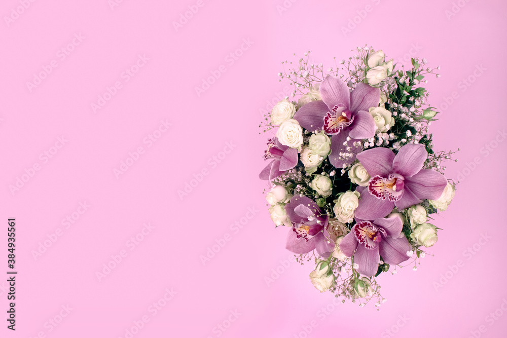 Bouquet with pink orchids on pink background with copyspace - floral composition for greeting card mockup. Holidays, birthday, Valentines Day, Mother Day or International Women's Day celebration