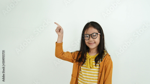Adorable little girl pointing at wall. Isolated on white background
