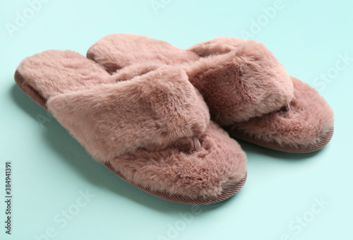 Pair of stylish soft slippers on turquoise background