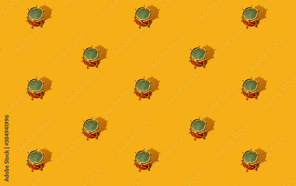 Orange Xmas background. Gold drum seamless pattern. Winter holidays ornament. Creative festive composition. Red toy music instrument arrangement isolated on bright yellow.