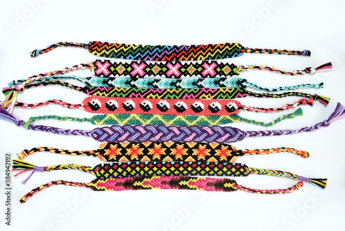 Woven DIY friendship bracelets handmade of embroidery bright thread with knots isolated on white background.