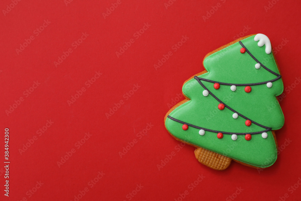 Christmas tree shaped gingerbread cookie on red background, top view. Space for text