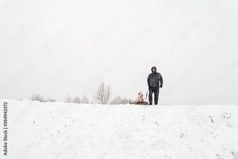 dad and daughter on a snow slide with tubing in a blizzard/ people in blur due to a shroud of snow