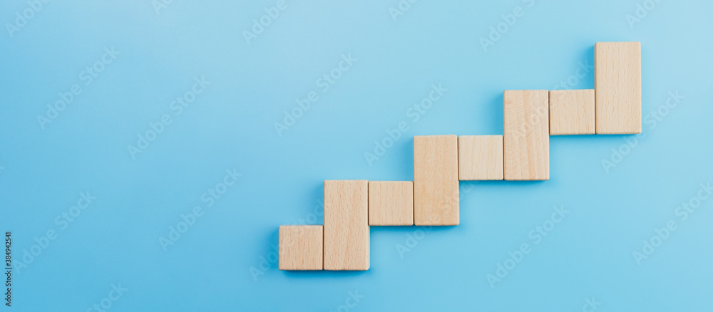 Wooden block stacking as step stair blue background, Ladder of success in business growth concept, copy space