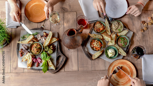 a large wooden table covered with oriental snacks and wine tasting lively by female hands 