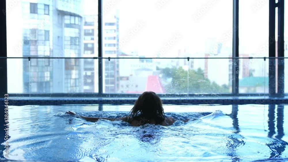 Close up of young woman is enjoying and having relax in swimming pool in a luxury wellness center.