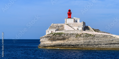 Panorama of red old lighthouse Phare de la Madonetta on a rock near Bonifacio Corsica against the sea and blue sky, copy space