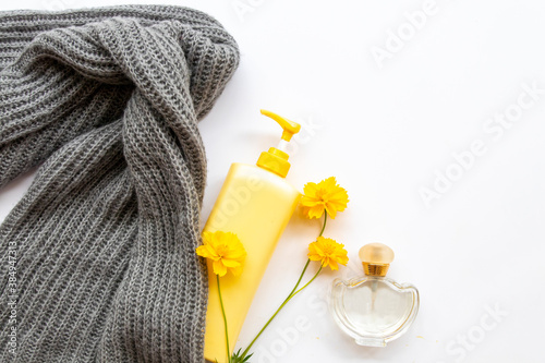 sunscreen body lotion health care for body skin,knitting wool scarf, perfume and yellow flowers cosmos of lifestyle woman relax winter arrangement flat lay style on background white 