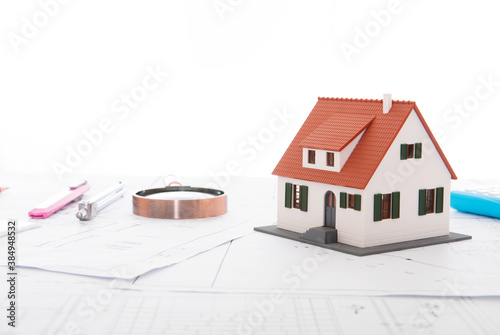 Small house model and magnifying glass and other related tools on architectural drawings