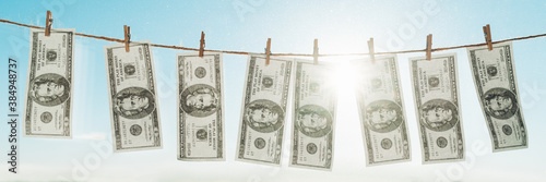 Money laundering concept banner. Panoramic of US dollards hanging to dry for laundry on clothesline.