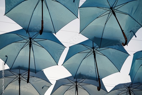 Low angle view on many hanging light blue umbrellas 