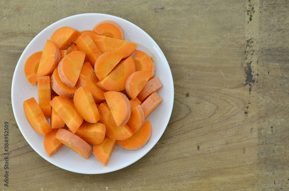Cut carrots thick in white plate on wooden background Cut carrots thick in white plate on wooden background
