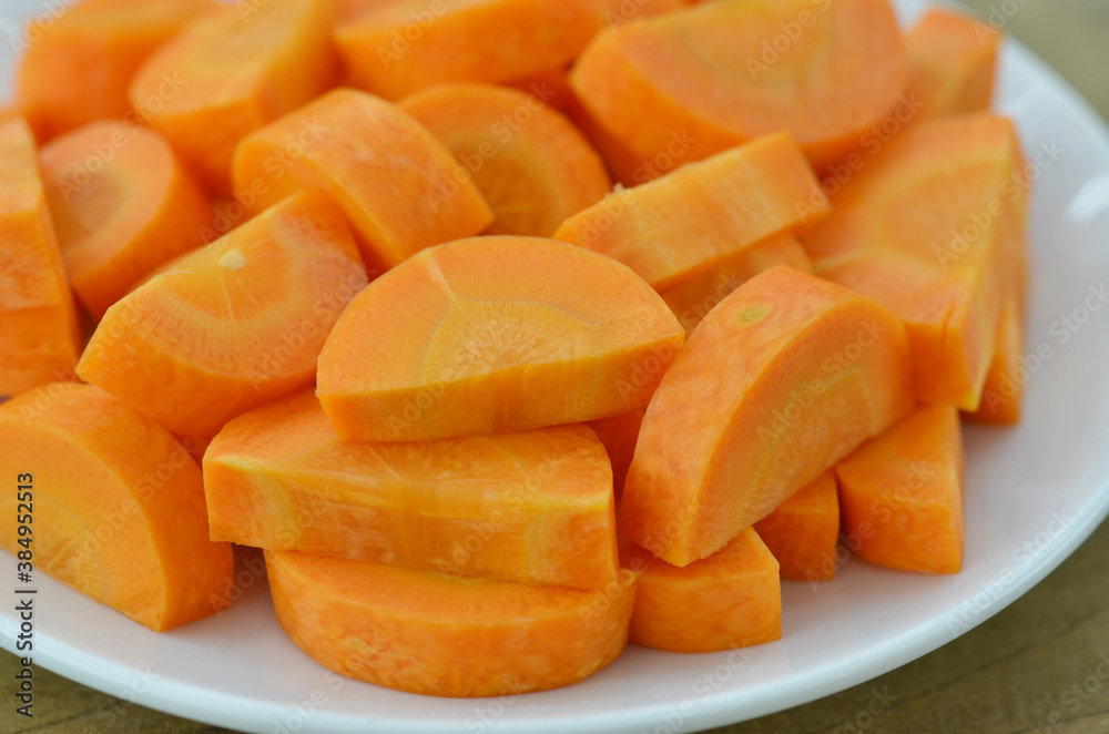 Cut carrots thick in white plate on wooden background Cut carrots thick in white plate on wooden background