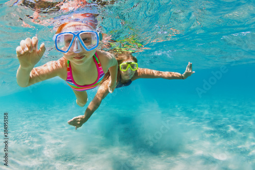 Billede på lærred Young mother with child in snorkeling mask dive in coral reef sea lagoon to explore underwater world