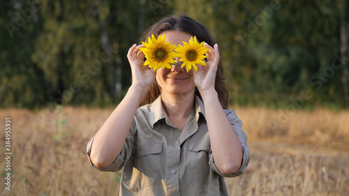 Young beautiful happy woman funny posing with sunflower flowers on a hot summer day