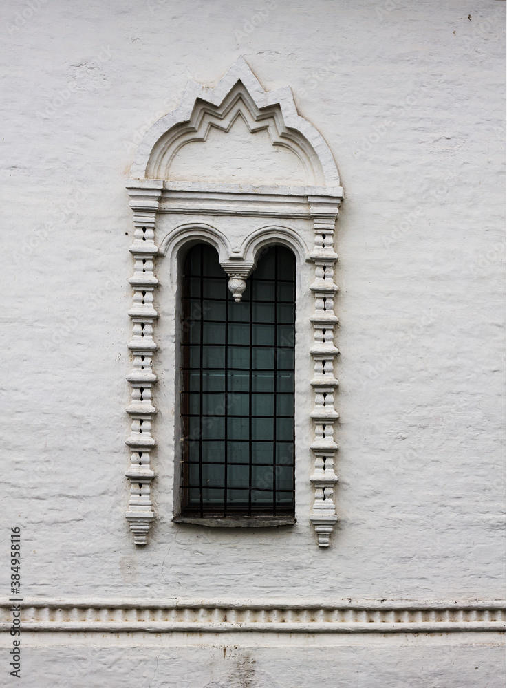 Obraz premium Old white stone window in the old Russian style. An old window of a 16th-century Church in Russia.