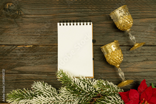 Happy New year 2021 celebration. Champagne glasses and blanck spyral notepad on wooden background. Flat lay.