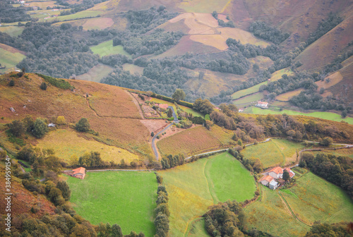 Village and road in mountains valley. Pyrenees, view from drone. Camino de Santiago landscape. Scenic meadows and agricultural fields in hill valley. Countryside in France. Travel and adventure.