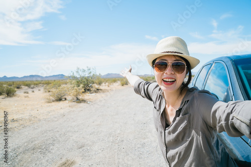 Fotografia asian woman by car having jolly laugh is taking selfie with wild nature in desert region