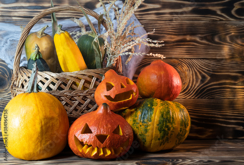 Halloween or Thanksgiving background with fresh fall pumpkins on straw lit by a burning lantern and sparkling part lights behind with copy space